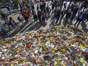 Pedestrians stop to look at floral tributes left by well-wishers on London bridge in London on June 9, 2017, following the June 3 terror attack that targeted members of the public on London Bridge and Borough Market (Niklas Halle'n/AFP)
