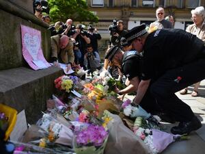 Police officers relocate floral tributes in St Ann's Square in Manchester, northwest England on May 23, 2017, laid as a mark of respect to those in killed and injured following a deadly terror attack at the concert at the Manchester Arena the night before. (AFP/Ben Stansall)