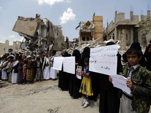 Yemenis stand in protest amidst the debris of a house, hit in an air strike on a residential district, in the capital Sanaa on August 26, 2017 (AFP)