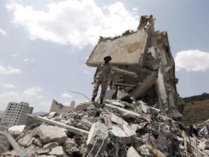 A Yemeni soldier stands on the debris of a house, hit in an air strike on a residential district, in the capital Sanaa on August 26, 2017 (AFP)