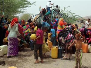 Yemenis gather next to a water tank to collect water in an impoverished coastal village on the outskirts of the Yemeni port city of Hudaydah, on May 12, 2018. (AFP Photo)
