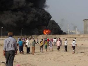 أشخاص يتجمعون في موقع اشتعال نيران بسبب قذائف أطلقها مقاتلون حوثيون على صهاريج تخزين النفط في عدن
