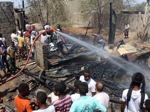 Yemenis extinguish fire at the scene of two suicide blasts which provoked the explosion of a motorbike in Dar Sad, north of the southern Yemeni port city of Aden, on March 16, 2016. (Saleh al-Obeidi)