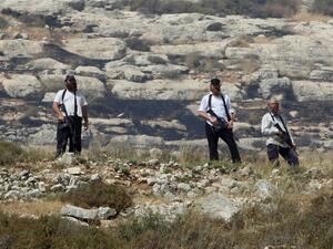 Israeli settlers wielding automatic rifles stand guard near an illegal Israeli settlement. (AFP/File)
