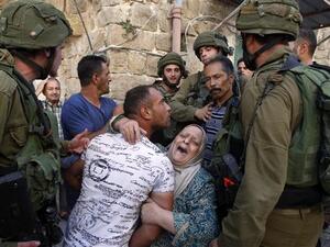 A Palestinian woman tries to prevent the arrest of a Palestinian man by Israeli soldiers in the southern occupied West Bank city of al-Khalil (Hebron) on September 20, 2016. (AFP)