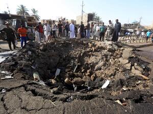 Bystanders look at the destruction caused by a car bomb outside of Baghdad earlier this year. (AFP/File)