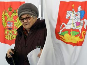 An elderly woman walks out of a voting booth at a polling station during Russia's presidential election (AFP/File Photo)