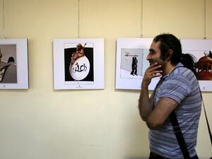 An Iranian man looks at cartoons displayed during an exhibition as part of the Daesh International Cartoon and Caricature Contest on May 31, 2015 at the Arasbaran gallery in Tehran. The exhibition displays the work of international cartoonists focusing on the crimes committed by Daesh in Syria and Iraq. (AFP/Atta Kenare)