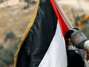 فلسطيني يرفع علما وطنيا ويضع كمامة خلال مشاركته في تظاهرة في بعلين في الضفة الغربية المحتلة