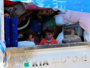 A displaced Iraqi family sit in the back of a truck in a queue for security checks as some 250 families return to their homes in Iraq's Anbar province on March 29, 2016. (AFP/Moadh al-Dulaimi)