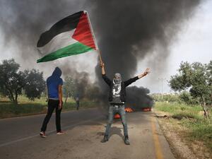 Palestinian demonstrators burn tires during a protest against the nearby demonstration by Israeli right-wing activists calling on Israel to release the suspected Jewish extremists of the July 2015 firebombing the home of a Palestinian family which killed a toddler and both his parents, on April 5, 2016. (AFP/Menahem Kahana)