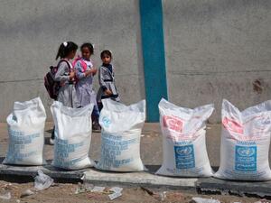 Palestinian Kids pass beside sacks of flour in Gaza Strip. (AFP/ File Photo)