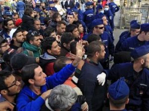 أفراد من الشرطة المجرية يراقبون مهاجرون يصطفون للصعود إلى القطار في بودابست يوم الأربعاء
