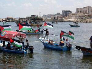 Palestinians hold their national flag as they ride boats during a rally to show support for activists aboard the flotilla (AFP Photo/Mahmud Hams)

