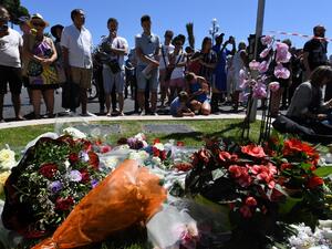 People stand on July 15, 2016 in front of a display in memory of those killed in Nice where a gunman smashed a truck into a crowd of revelers celebrating Bastille Day. (AFP/Boris Horvat)