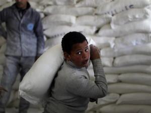 طفل فلسطيني يحمل كيس طحين في مركز توزيع اعانات الانروا/أ.ف.ب