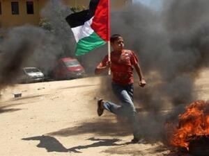 طفل فلسطيني يرفع العلم الفلسطيني ويقفز عن اطار مشتعل اثناء تدريب في غزة/أ.ف.ب