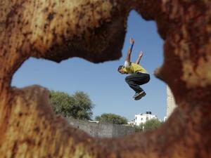 شاب من غزة يمارسة رياضة القفز على سور مهدم/أ.ف.ب