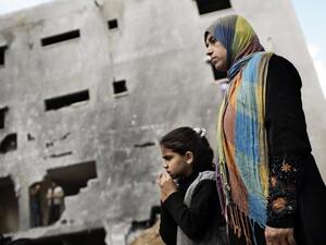 فلسطينية وابنتها تنظران الى منزل ال الدلو الذي قصفته اسرائيل خلال العدوان /أ.ف.ب