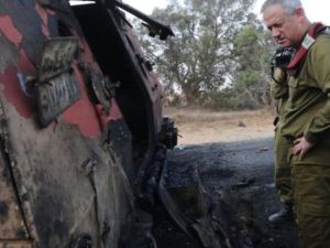 ضابط اسرائيلي يقف امام سيارة دمرها الطيران الاسرائيلي كان يستقلها عدد من منفذي الهجوم/أ.ف.ب