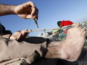 صياد فلسطيني يصلح شباكه على بحر رفح/أ.ف.ب