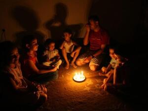 عائلة فلسطينية تتحلق حول الشموع بعد انقطاع الكهرباء عن غزة امس السبت/ا.ف.ب