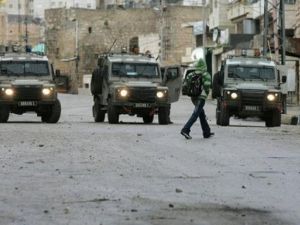 فتى فلسطيني يمر امام مدرعات اسرائيلية في الخليل في الضفة الغربية
