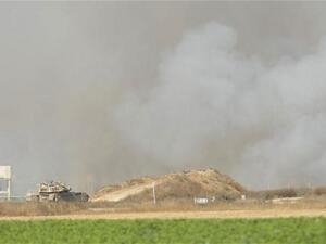 دبابة اسرائيلية ترصد الحدود الجنوبية لغزة فيما تبدو اثار قصف الطيران من بعيد/أ.ف.ب