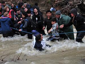 Migrants and refugees cross a river on their way to Macedonia from a makeshift camp at the Greek-Macedonian border on March 14, 2016, where thousands are stranded by the Balkan border blockade. (AFP/Sakis Mitrolidis)