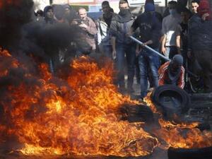 صبي فلسطيني يرتدي قناعا يشعل النار في إطار خلال اشتباكات مع قوات اسرائيلية في الخليل بالضفة الغربية
