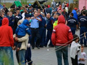 Hungarian police officer directs the migrants in the refugee camp of the Hungarian-Serbian border Roszke village on August 26, 2015. (AFP/Csaba Segesvari)