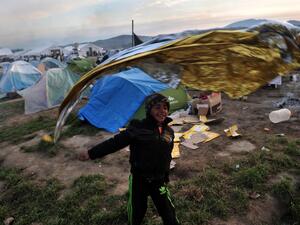 A child plays with a survival blanket at the makeshift camp at the Greek-Macedonian border, near the Greek village of Idomeni on March 26, 2016, where thousands of refugees and migrants are stranded by the Balkan border. (AFP/Sakis Mitrolidis)