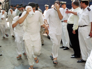 Egyptian men, accused of having gay sex, cover their faces as they walk into a Cairo court 18 July 2001 (AFP File Photo/Andrew Black)