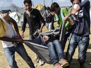 Migrants and refugees carry a man injured during clashes with Macedonian soldiers near their makeshift camp in the northern Greek border village of Idomeni, on April 10, 2016. (AFP/Bulent Kilic)