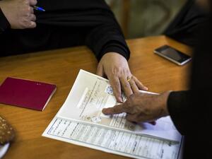An Iranian woman presses her inked-finger on a registering paper during the parliamentary and Assembly of Experts elections at a polling station at Massoumeh shrine in the holy city of Qom, south of the capital Tehran, on Feb. 26, 2016. (AFP/Behrouz Mehdi)