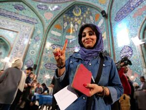 An Iranian woman shows her inked finger after casting her ballot at a polling station in Tehran on February 26, 2016. (AFP/Atta Kenare)