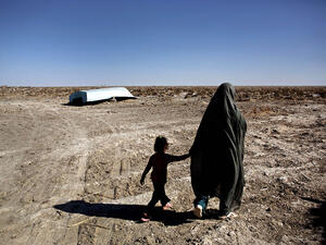 An Iranian woman and her daughter walk past an abandoned boat in the village of Sikh in the Hamoun wetland, where once-flourishing plants and animals have been killed by drought, on Feb. 2, 2015. (AFP/File)