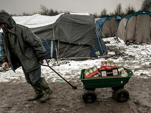 A man carries food at the refugee and migrant camp in Grande-Synthe near Dunkirk, northern France, where 2,500 refugees from Kurdistan, Iraq and Syria live. (AFP/File)