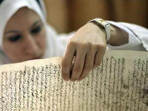 موظفة في المكتبة الوطنية العراقية تتفحص مخطوطا عثر عليه في مكتبة بغداد بعيد الغزو الاميركي
