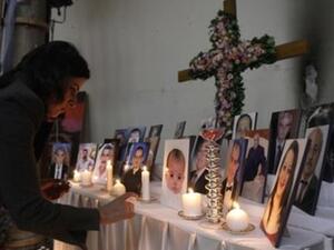 امراة تشعل شمعة وسط صور لمسيحيين عراقيين فتلى في كنيسة سيدة الخلاص في بغداد
