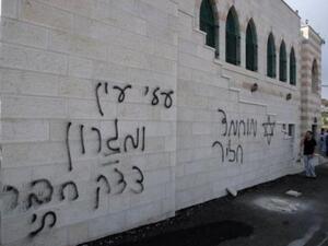 فلسطيني يتكلم على الهاتف في 5 ايلول/سبتمبر الى جانب كتابات بالعبرية على جدار مسجد في الضفة الغربية
