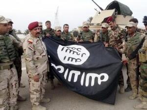 قوات أمن عراقية تحمل علم الدولة الاسلامية الذي خلفه التنظيم بعد انسحابه من مدينة الرمادي
