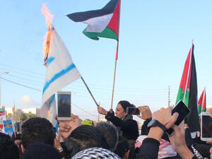 محتجون يحرقون علم "اسرائيل" خلال الاعتصام أمام السفارة الأميركية في عمان