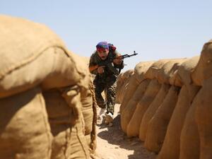 A fighter from the Kurdish People Protection Unit (YPG) walks between sandbags on the front line in the northeastern Syrian city of Hasakeh on September 4, 2015 (AFP/Delil Souleiman)
