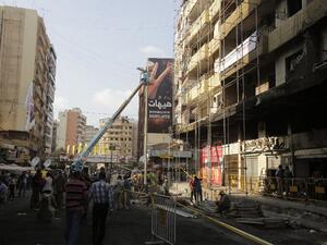 LEBANON, Beirut : Workers from Jihad al-Binaa, a construction company affiliated with the Shiite Muslim Hezbollah movement, clear up the neighbourhood where a car bomb exploded the previous week in a southern Beirut stronghold of the pro-Syria Shiite group on August 19, 2013.  AFP PHOTO/JOSEPH EID