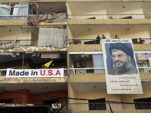 LEBANON, Beirut : Lebanese people hand a poster of Hassan Nasrallah, the head of Lebanon's militant Shiite Muslim movement Hezbollah, from their balcony. AFP PHOTO / ANWAR AMRO