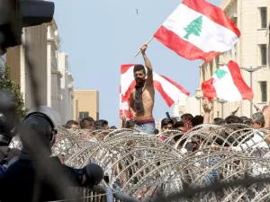 Lebanese protesters wave the national flag in front of a barbed wire fence as large crowds rally in Beirut on August 23, 2015. (Anwar Amro/ AFP)