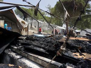 A man walks through the burned tents after a riot at a Lesbos detention center. (AFP/Stringer)