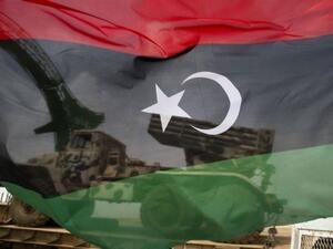 A Libyan flag flown in front of a military vehicle. (AFP/File)