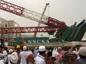 Pilgrims walk near the construction crane which crashed in Mecca's Grand Mosque on September 11, 2015, killing more than 100 and injuring over 200 others. (AFP)